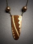 “Chevrons”; U shaped Copper pendant with 3 bronze inlaid chevrons of various sizes measuring 2”h x 1 ¼”w. Hangs on adjustable bronze chain embellished with a hollow bronze bead on each side of pendant.