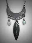 Steel Crescent Pendant - Leaf ; L=  2 ½”   W= 1 3/8”;   Hand sculpted steel crescent pendant.  From the steel crescent hangs a 1 ½” steel leaf and flanked by two 6x9mm Labradorite gemstones and Pyrite beads.  Hangs on a 22” chain.